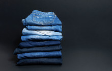 Stack Of Various Blue Jeans On Black Background. Beauty And Fashion, Clothing Concept. Detail Of Nice Blue Jeans. Jeans Texture Or Denim Background. Collection Of Jeans.