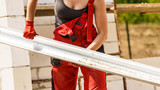 Fototapeta Do pokoju - Woman carrying gutter on construction site
