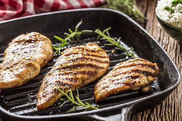 Grilled chicken breast in grill pan with herbs.