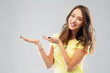 © Syda Productions - people concept - smiling young woman or teenage girl in blank yellow t-shirt holding something imaginary over grey background