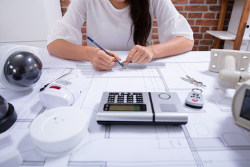 Female Architect Drawing Blueprint With Pencil