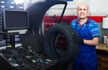 Sticker - Mature male technician holding car wheel ready to work with balancing machinery at workshop