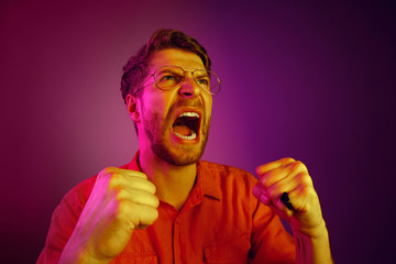 Screaming, hate, rage. Crying emotional angry man screaming on pink studio background. Emotional, young face. male half-length portrait. Human emotions, facial expression concept. Trendy neon colors