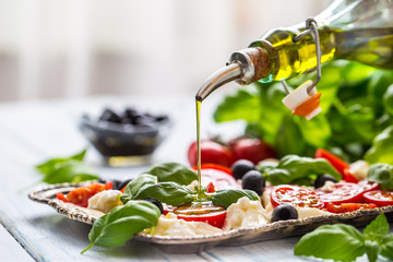 Wall Mural - Pouring olive oil on caprese salad. Healthy italian or mediterranean meal