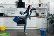 Full length view of shoked woman in jeans dealing with water leak in kitchen