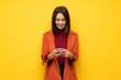 © luismolinero - Young woman with coat sending a message with the mobile