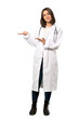 © luismolinero - A full-length shot of a Young doctor woman presenting an idea while looking smiling towards over isolated white background