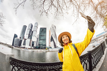 Wall Mural - Young woman taking photo on her smartphone in business center skyscrapers in big city