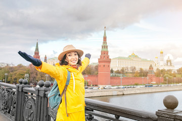 Happy asian woman tourist on the background of the Kremlin wall tower from the Moscow river embankment. Travel in Russia concept