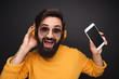 © kegfire - Bright hipster man in headphones holding smartphone