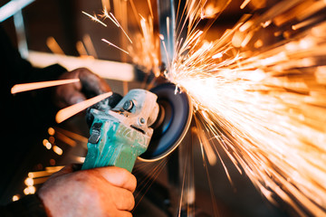 construction industry details - metalworker using disc grinder for cutting metal