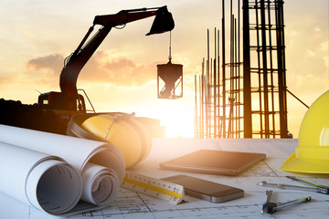 Desk of civil engineer with background silhouette of excavator activity machine