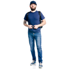 Wall Mural - A man photographer in jeans and cap, black backpack standing looking on white background isolation