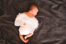 Cute Sleeping Baby Wearing White Angel Wings Over Dark Background. Childhood. Good Morning.