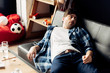 © LIGHTFIELD STUDIOS - tired man lying on sofa and having hangover after party