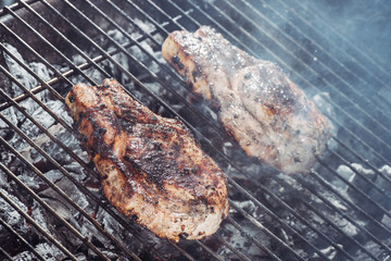 Poster - selective focus of juicy steaks grilling on hot coals with smoke