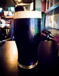 © Whales Factory - Dark stout beer on a pub background with colored lights from the environment