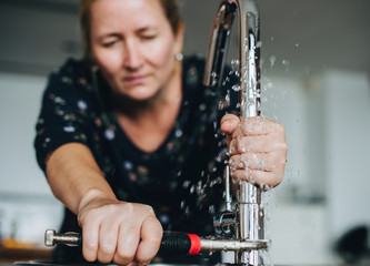 Wall Mural - Handy woman fixing the faucet