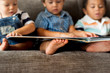 © Rawpixel.com - Three little boys reading a book on a sofa