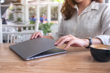 Closeup image of a woman close and open a laptop computer on table after finished using it