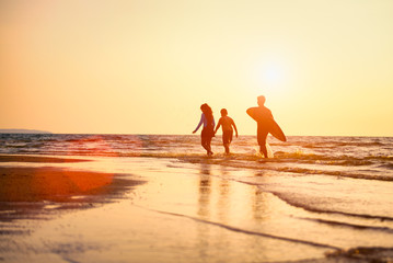 Silhouette of Young surfers with brethren they're relaxing on sunset beach. Summer activity of people on the beach concept. Extreme sports concept.