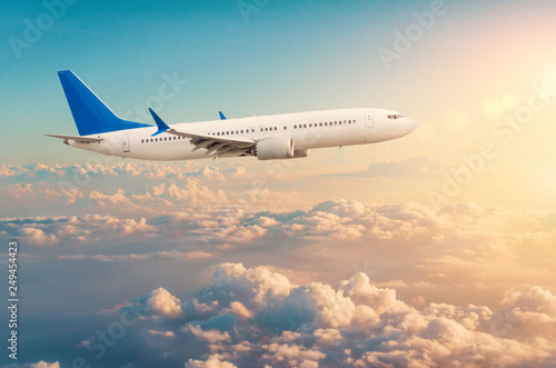 Fotografía Commercial airplane flying above cloudscape in dramatic toned sunset light