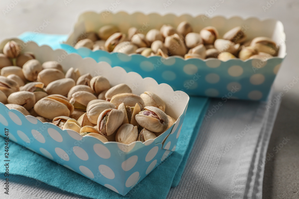 Paper boxes with tasty pistachio nuts on grey table