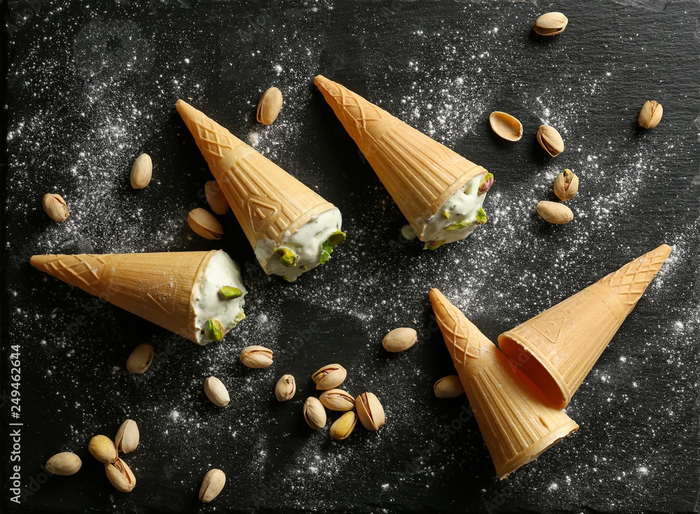 Wafer cones with tasty pistachio ice-cream on dark background