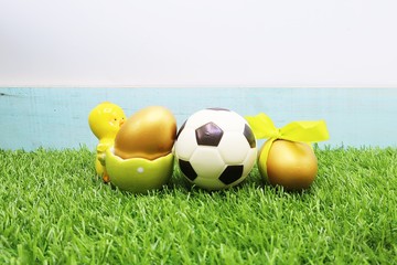 Football with Easter eggs are on green grass