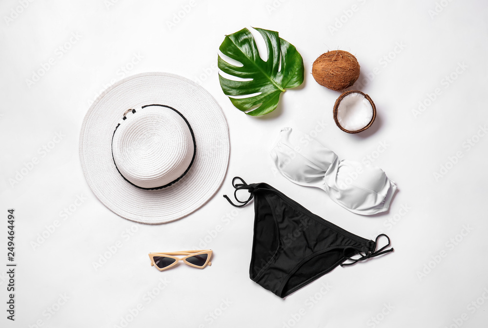 Female swimsuit with accessories, tropical leaf and coconut on white background - obrazy, fototapety, plakaty 