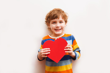 Wall Mural - smiling little child six years old holds paper heart on white background. happy mother's day!