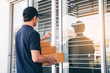 © wutzkoh - Young asian courier is using the hand of the knock at the door to deliver the goods.