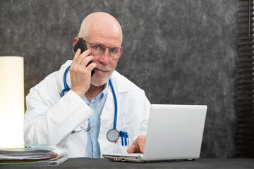 Mature smiling bearded doctor talking on phone