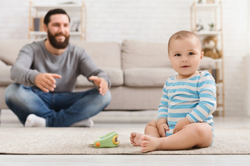 Wall Mural - Father playing with his baby son on floor at home