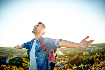 Wall Mural - Freedom concept. Handsome man outstretching arms while hiking with backpack