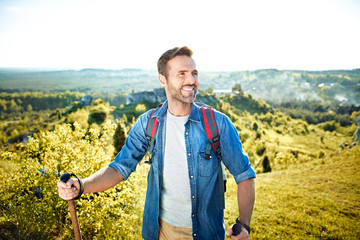 Wall Mural - Happy man hiking with poles during beautiful summer day