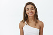 Cute stylish and carefree attractive african american female student with dreads and braces smiling broadly enjoying expressing herself with daring cool outfits and looks over gray wall