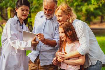 Wall Mural - Happy healthy family and doctor talking in the park. People healthcare and medical staff service concept.