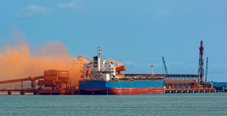 Loading bulk carrier ship with bauxite aluminum ore at Kamsar port, Guinea.