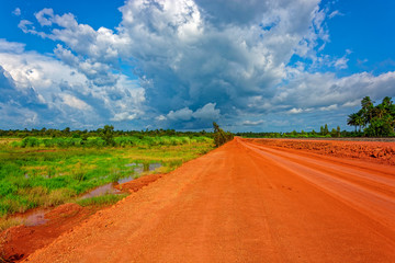 Typical red soils unpaved rough countryside road in Guinea, West Africa.