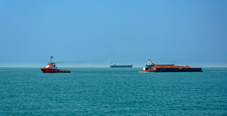 Canvas Print - Tug boat with a large cargo barge transporting bauxite ore in Kamsar, Guinea.