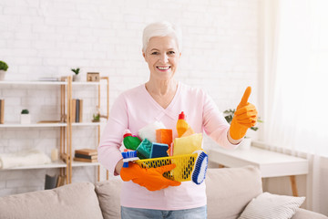 Smiling mature housewife cleaning floor at home