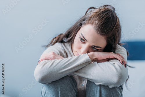 Fotografía selective focus of beautiful sad woman hugging knees and looking away
