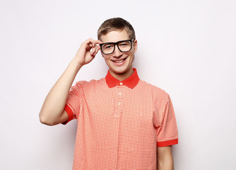 Wall Mural - Portrait of a smart young man wearing eyeglasses standing against white background