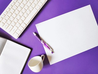 Flat lay office supplies. Top view photo purple desktop. Open paper notebook, white computer keyboard, pen and cup of coffee. Mockup with free space for text 