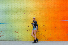 Portrait Of Young Woman With Cell Phone At Colorful Brick Wall
