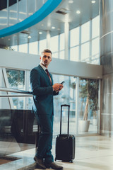 Wall Mural - Man with suitcase using telephone and waiting departure on trip