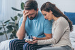 © LIGHTFIELD STUDIOS - selective focus of grieving parents sitting on bed and holding baby shoes at home