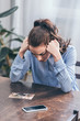 © LIGHTFIELD STUDIOS - sad woman in blue blouse sitting at table with smartphone and looking at photo at home, grieving disorder concept