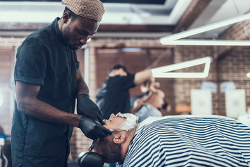 Canvas Print - Concentrated man shaving client with foam on face